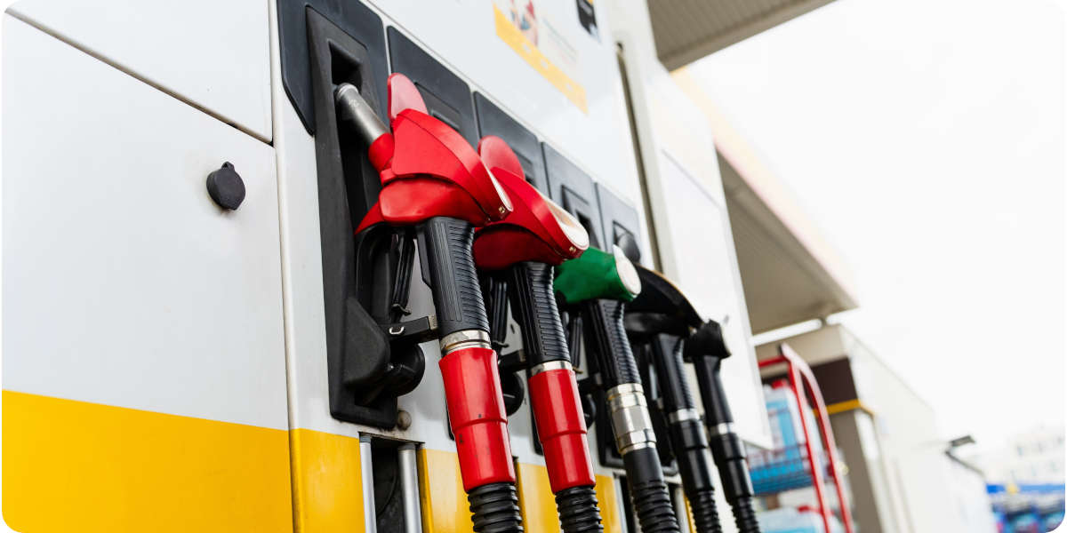 Fotografier von Zapfpistolen in Rot, Gr&uuml;n und Schwarz an einer Zapfs&auml;ule einer Tankstelle