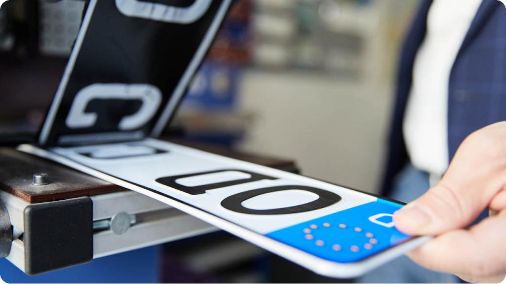 Ein Mitarbeiter von Kroschke foliert Autokennzeichen.